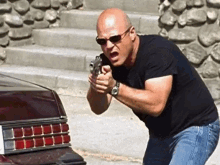 a bald man is pointing a gun at a car