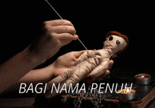 a person is holding a stuffed doll with pins in it and the words bagi nama penuh written above it