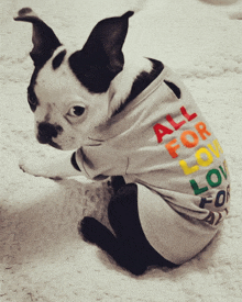 a black and white dog wearing a shirt that says " all for love "