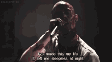 a man is singing into a microphone with a bloody arm and a quote .