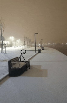 a stick figure sits on a bench in the snow at night