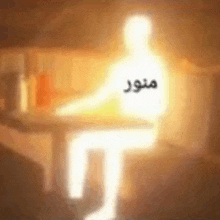 a silhouette of a person sitting at a table with a light coming out of it .