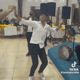 a man is dancing in a room with a drum and a tiktok logo