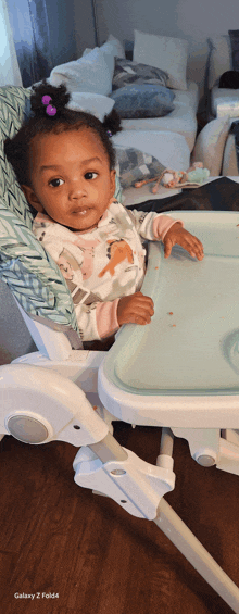 a baby is sitting in a high chair with a galaxy 2 fold written on the bottom