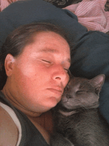 a woman laying on a bed with her eyes closed holding a cat