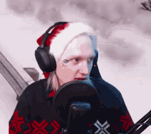 a man wearing a santa hat and headphones is speaking into a microphone .