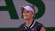 a woman wearing a purple visor and a black nike shirt smiles