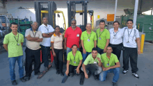 a group of people posing for a picture in front of a forklift that says peso on it