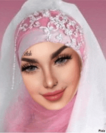 a woman is wearing a pink hijab and a white veil .