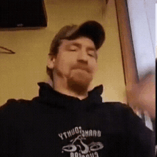 a man with a beard wearing a hat and a black hoodie that says ythuo on it .