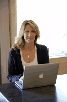 a woman is sitting at a desk with an apple laptop