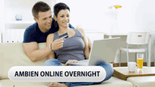 a man and woman are sitting on a couch with a laptop and a credit card