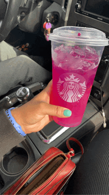 a person is holding a pink starbucks drink