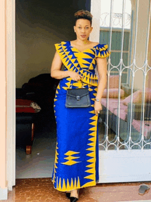 a woman in a blue and yellow dress is standing in front of a glass door