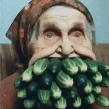 an old woman is eating a bunch of cucumbers .