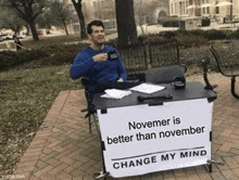 a man is sitting at a desk with a sign that says november is better than november