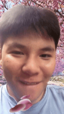 a close up of a man 's face with a pink flower in the background