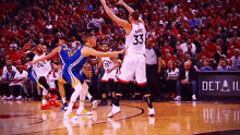 a group of basketball players are playing a game of basketball on a court in front of a crowd .