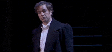 a man in a tuxedo is standing on a stage .