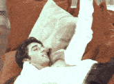 a man laying on a couch with a white pillow on top of him