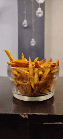 a glass bowl of french fries sits on a table