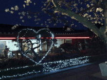 a tree with a heart made of lights in front of a house