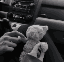 a person is holding a teddy bear in front of a car radio that says 47.5