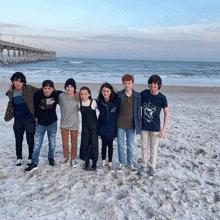 a group of young people standing on a beach with one wearing a shirt that says n on it