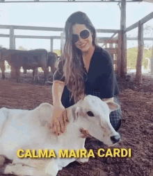 a woman is petting a baby cow in a stable .