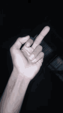 a person 's hand is giving the middle finger sign