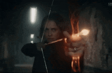 a woman is holding a bow and arrow in her hand .