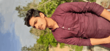 a young man wearing a purple shirt is standing on a rock