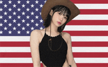 a woman wearing a cowboy hat stands in front of a large american flag