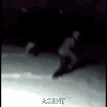 a person is skating on a ice rink in the dark and the word agent is visible in the corner .