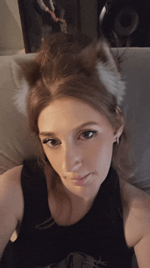 a woman wearing a cat ear headband is laying on a bed