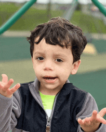 a young boy wearing a black jacket and a green shirt