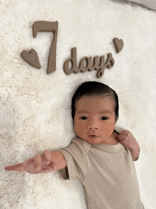 a newborn baby is laying on a blanket with the words 7 days written on it