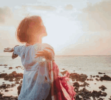 a woman is standing on a beach with her arms outstretched .