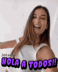 a woman in a white tank top is smiling and says hola a todos !!