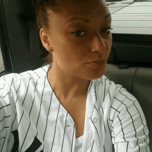 a woman wearing a ny yankees jersey takes a selfie in a car