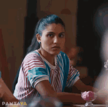 a woman in a striped shirt sits at a table with a bowl of ice cream and the word pantaya on the bottom