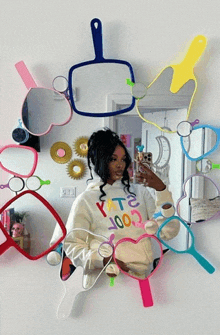 a woman taking a selfie in front of a mirror that has a heart shaped hand mirror