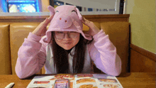 a woman wearing a pig hat looks at a menu at a restaurant