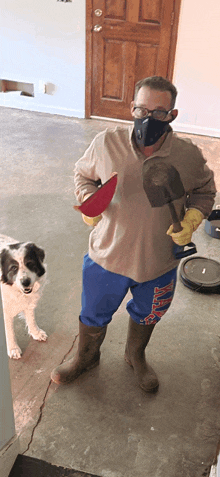 a man wearing a mask is standing next to a dog whose shorts say duke