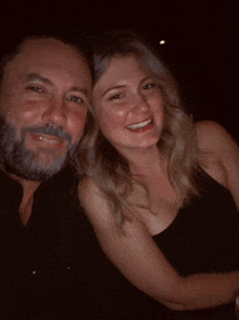 a man with a beard and a woman in a black dress are posing for a picture