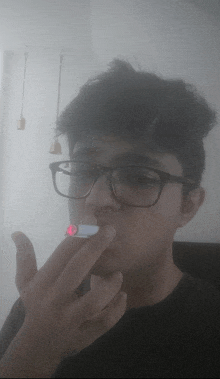 a man wearing glasses is smoking a cigarette with a red light on it