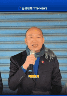 a man in a suit and scarf is holding a microphone in front of a sign that says tv news