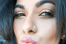 a close up of a woman 's face with a nose ring and makeup .