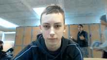 a young man in a black hoodie stands in front of lockers