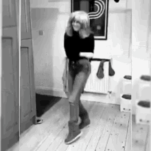 a black and white photo of a woman dancing in a hallway in a room .